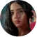 A woman with glasses and a pink flower in her hair.